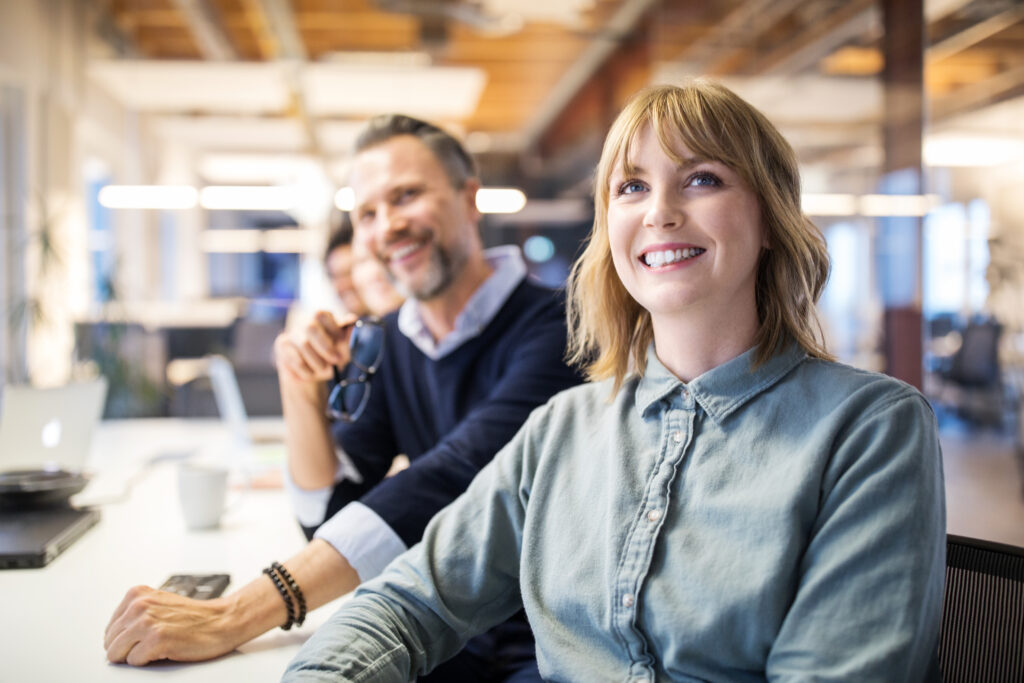 Business woman with colleagues sitting at board room table and paying attention to the meeting.
